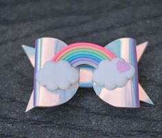 a bow brooch with a rainbow and clouds on it