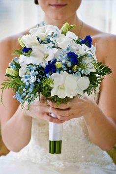 a woman holding a bouquet of white and blue flowers