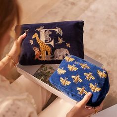 a woman is holding a blue purse with gold embroidered animals and bees on the front