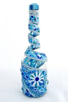 a blue and white mosaic glass bottle with a spiral design on the top, in front of a white background