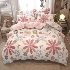 a bed with pink and blue flowers on it in a room next to a window