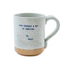 a white and brown coffee mug with blue writing on the inside, in front of a white background