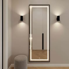 an illuminated mirror in the middle of a room with two lights on either side of it