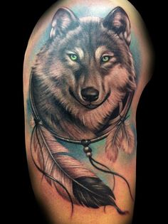 a wolf with feathers on his head and eyes is shown in this tattoo art piece