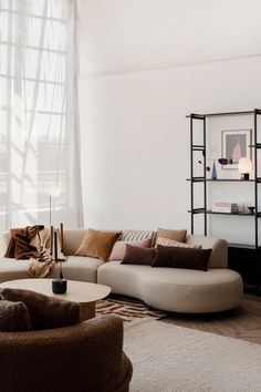 a living room filled with lots of furniture next to a large window and white walls