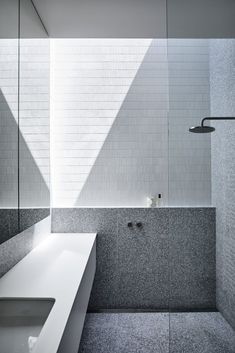 a white sink sitting under a window next to a bath tub in a room with tiled walls