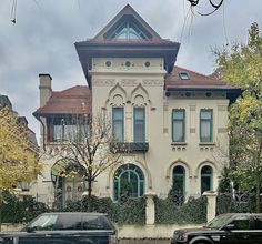 two cars parked in front of a large house