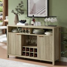 a dining room table with wine glasses and plates on it, in front of a green wall