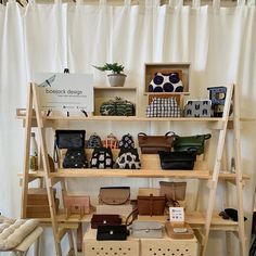 the shelves are filled with purses and handbags on display in front of a white curtain