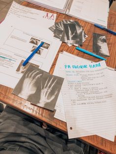 a table topped with papers and pens next to a pair of gloves on top of a wooden table