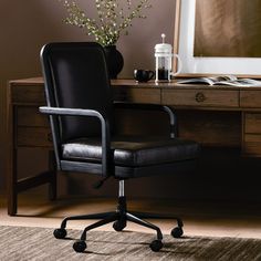 a black office chair sitting in front of a desk with a vase on top of it