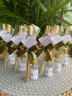 several small bottles with labels on them sitting on a table next to some plants and flowers