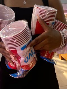 a woman is holding some cups in her hands