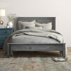 a bed sitting on top of a wooden floor next to a blue dresser and lamp