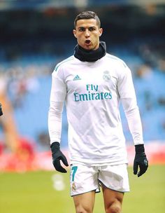 a soccer player is standing on the field with his hands in his pockets and wearing black gloves