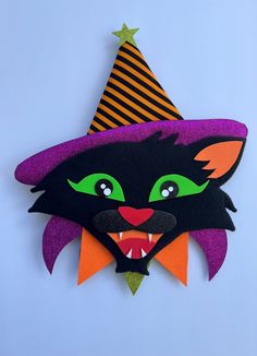 a black cat wearing a witch hat with green eyes and purple hair, on a blue background