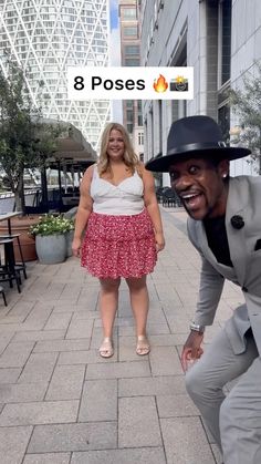 a man in a suit and hat posing for a photo with a woman on the sidewalk