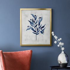 a blue and white painting hanging on the wall next to a chair with an orange cushion