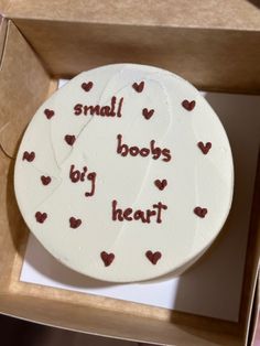 a small white cake in a box with red writing on it that says, small body by heart