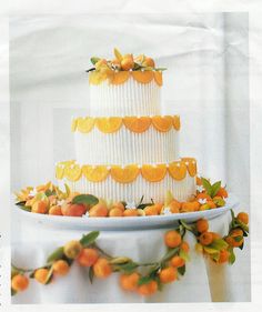 a three tiered white cake with oranges on top