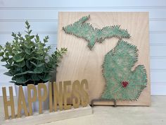 a wooden sign with the shape of a michigan on it next to a potted plant