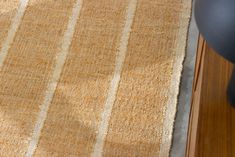 a close up of a rug on a wooden floor with a chair in the background