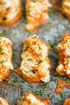 several pieces of bread with cheese and herbs on them sitting on a baking sheet, ready to be eaten