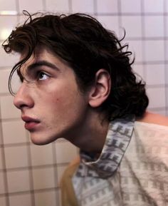 a close up of a person in a bathroom with tile walls and white tiles on the wall