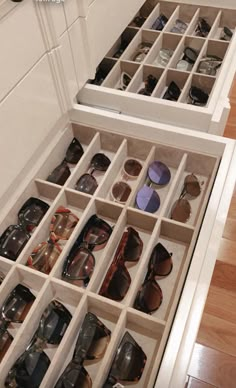 an open drawer filled with sunglasses on top of a wooden floor