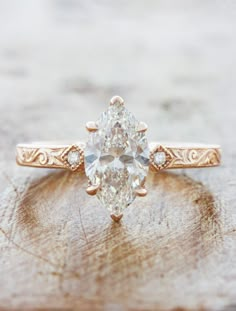 an oval shaped diamond ring on top of a wooden surface