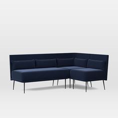 a blue sectional couch with black legs and pillows on it's back, in front of a white background