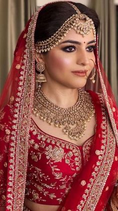 a woman wearing a red and gold bridal outfit