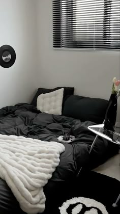 a black and white room with a bed, couch, table and window in it