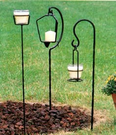 three candle holders in the shape of heart shaped candles are sitting on top of a flower bed