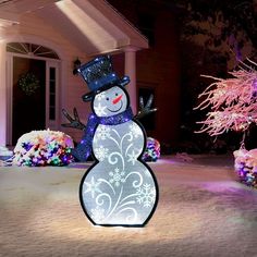 a lighted snowman in front of a house