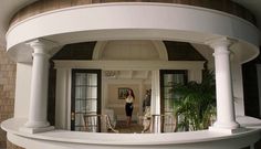 a woman is standing in the doorway of a house with columns on either side of it