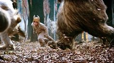 a young boy is running through the woods with two bears and another bear behind him