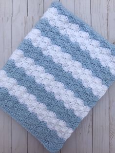 a blue and white crocheted blanket laying on top of a wooden floor