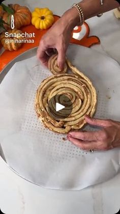 a person is making some food on a white tablecloth with pumpkins in the background