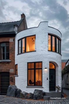 a white brick house with large windows on the front and side of it's face