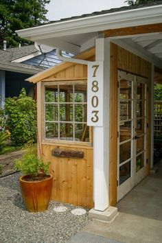 a small wooden building with a number on the door and windows in front of it