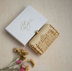 a white box with some flowers next to it and a lighter in the shape of a city