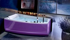 a purple bath tub sitting on top of a floor next to two pictures with candles in it