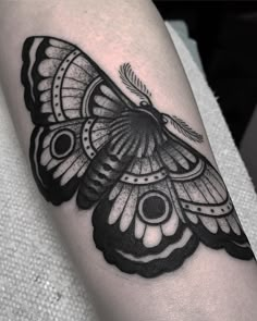 a black and white butterfly tattoo on the right arm, with an intricate wing design