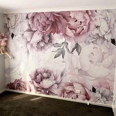 an empty room with flowers painted on the wall and stuffed animals in front of it