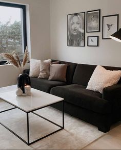 a living room with a couch, coffee table and pictures on the wall above it