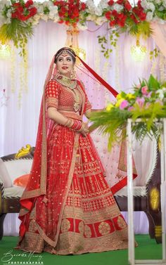 a woman in a red and gold bridal gown posing for the camera at her wedding ceremony