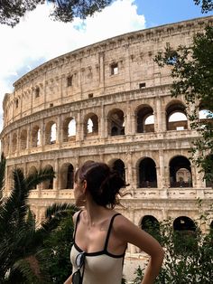 a woman standing in front of the colossion with her back turned to the camera