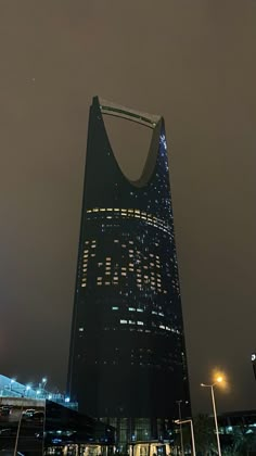 a tall building lit up at night with lights on it's side and the sky in the background