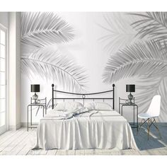 a white bedroom with palm leaves on the wall